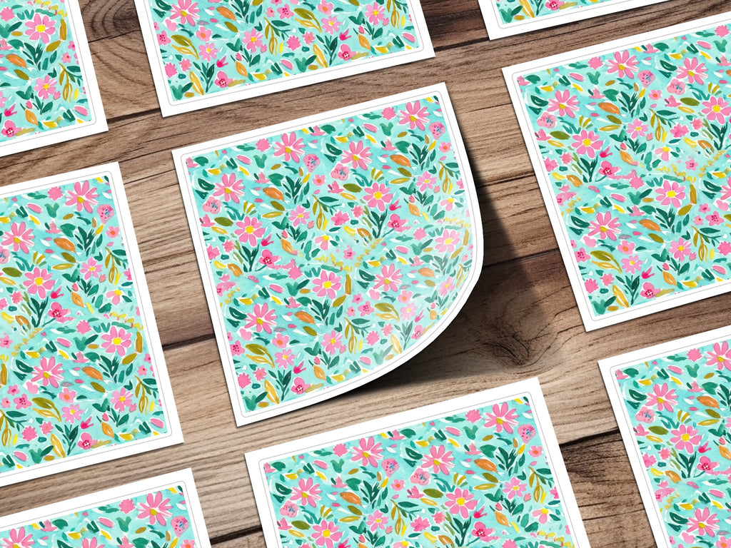 Pattern of small pink and green flowers on white cards, arranged on a wooden surface.