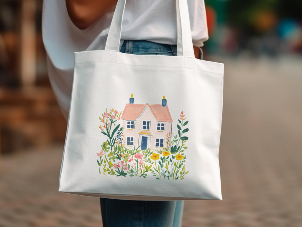 White tote bag with a watercolor illustration of a pink house and flowers.