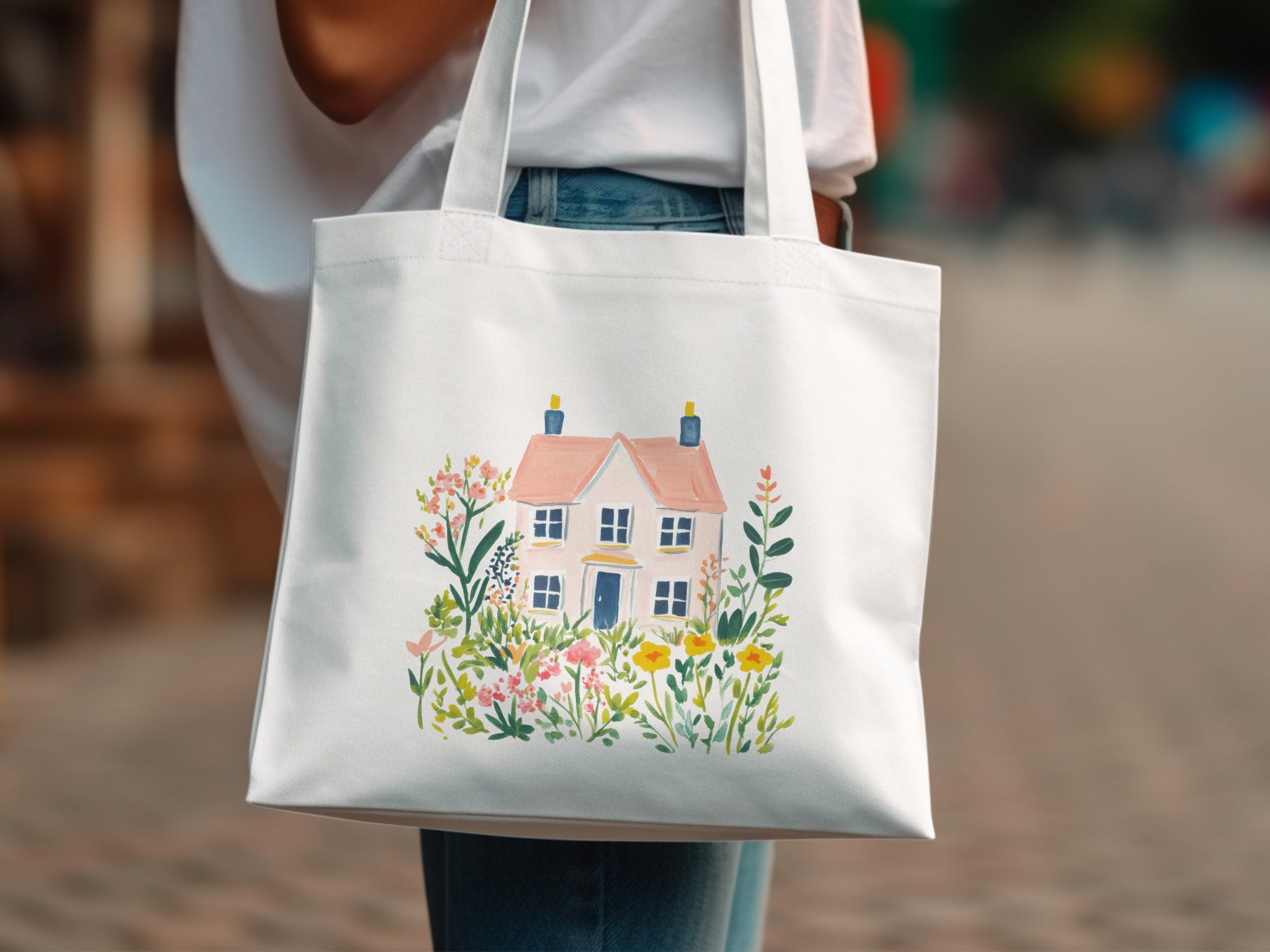White tote bag with a watercolor illustration of a pink house and flowers.