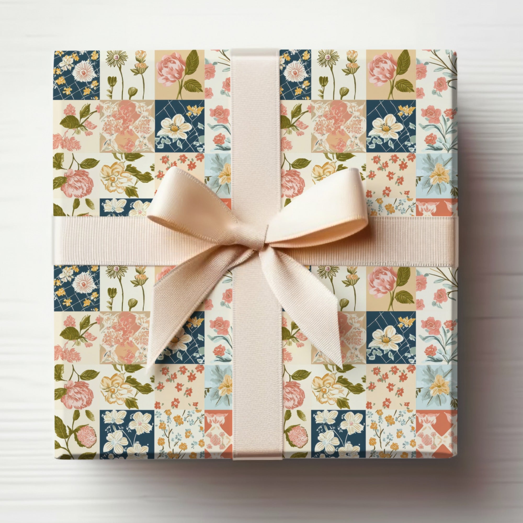 Gift box wrapped in floral patchwork paper with a beige ribbon and bow.