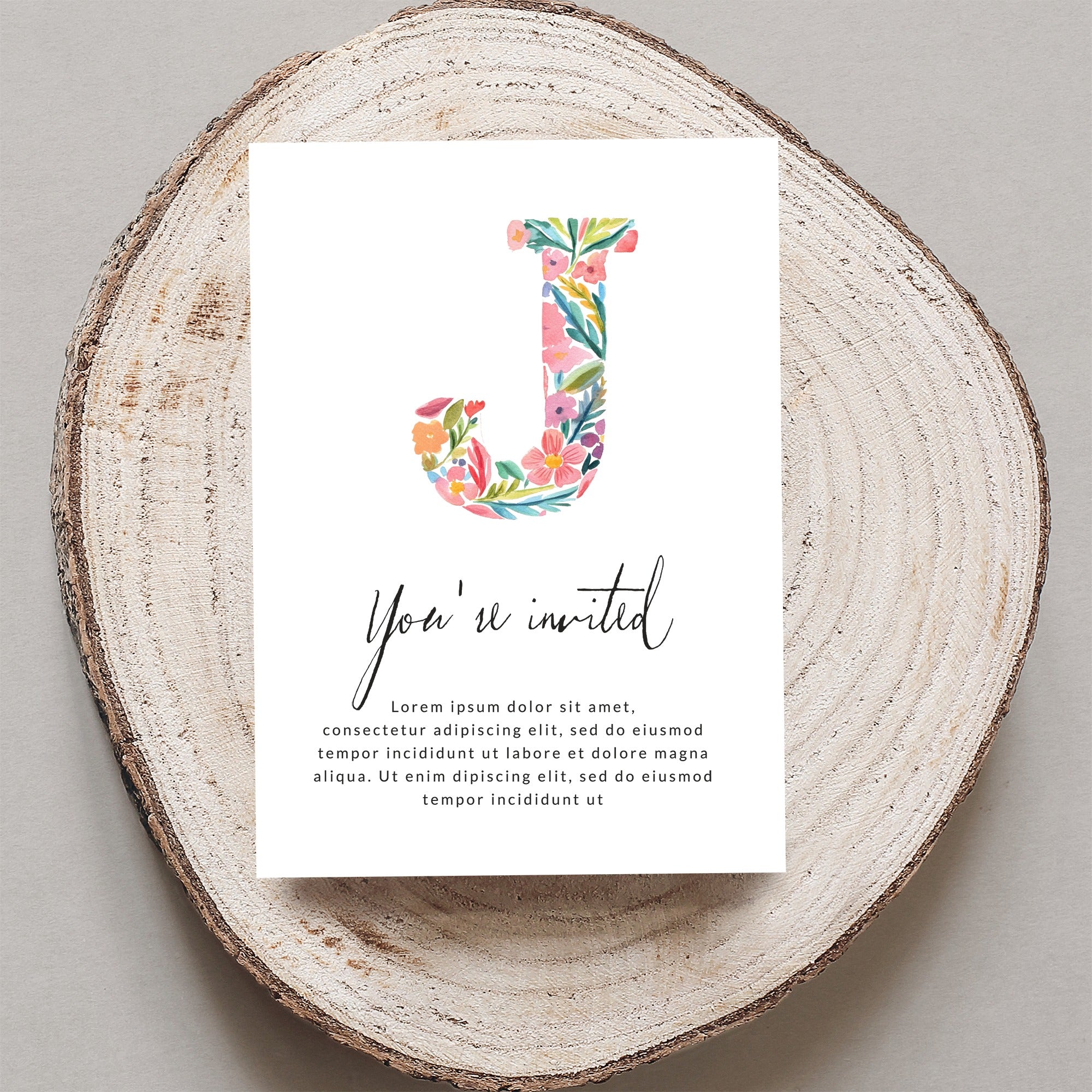 Floral initial 'J' on an invitation with "You're invited" text.