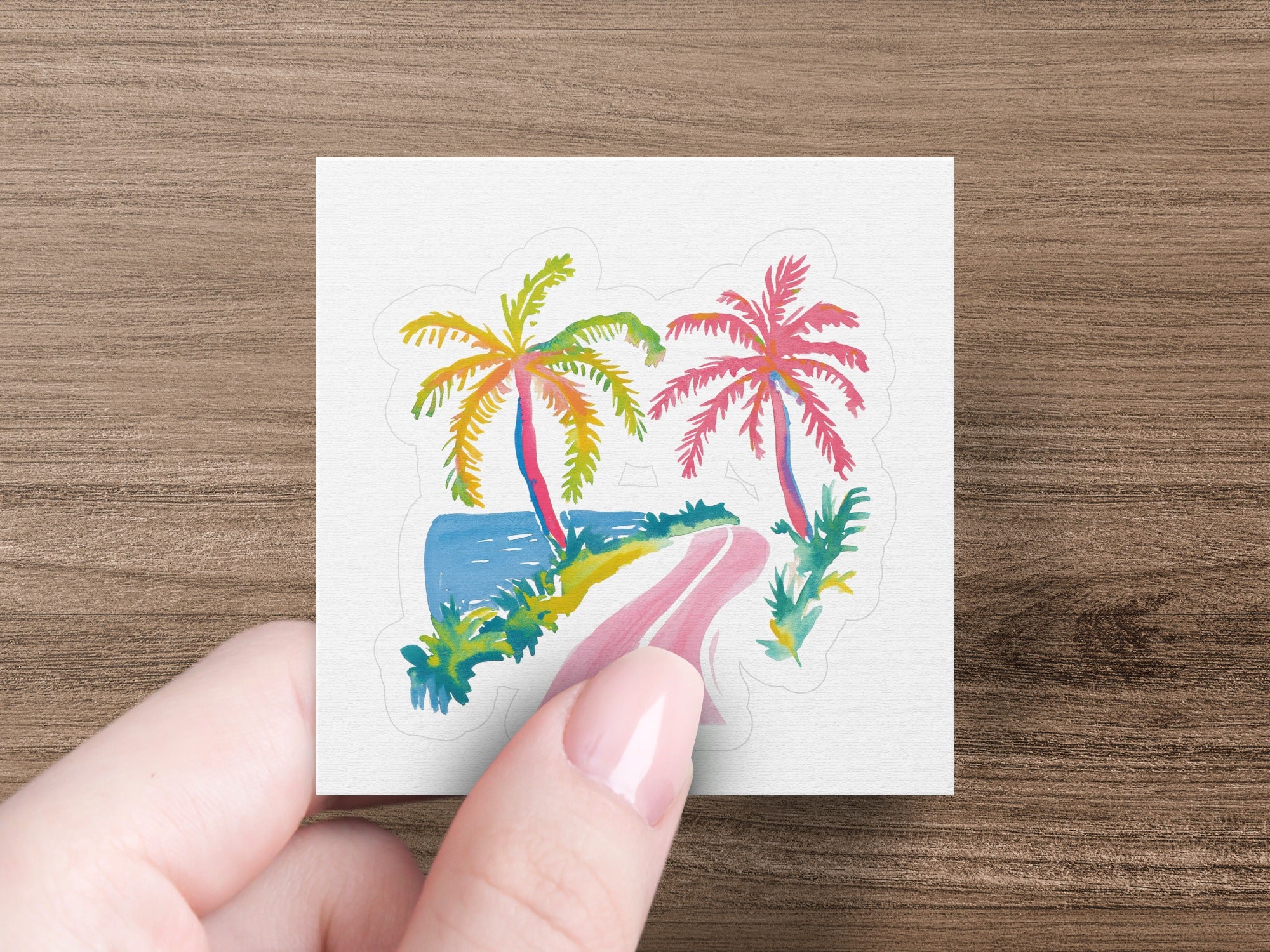 Hand holding a square sticker with a colorful tropical beach scene.