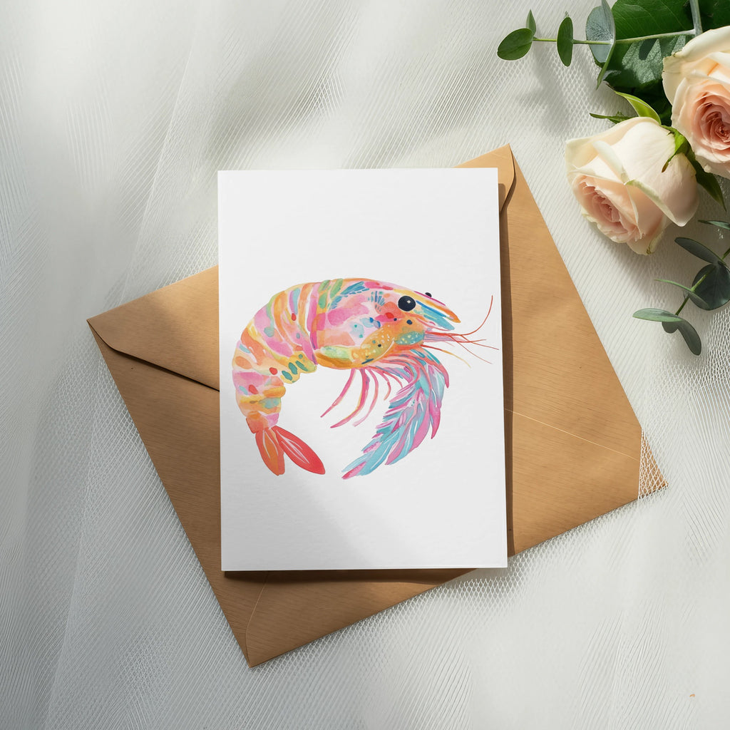 Colorful watercolor shrimp illustration on a card over a brown envelope.