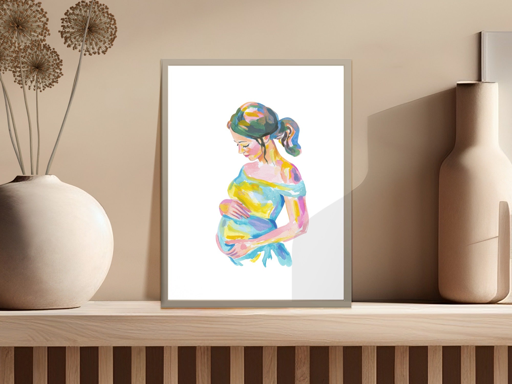 Watercolor painting of a pregnant woman with colorful dress, displayed on a shelf.