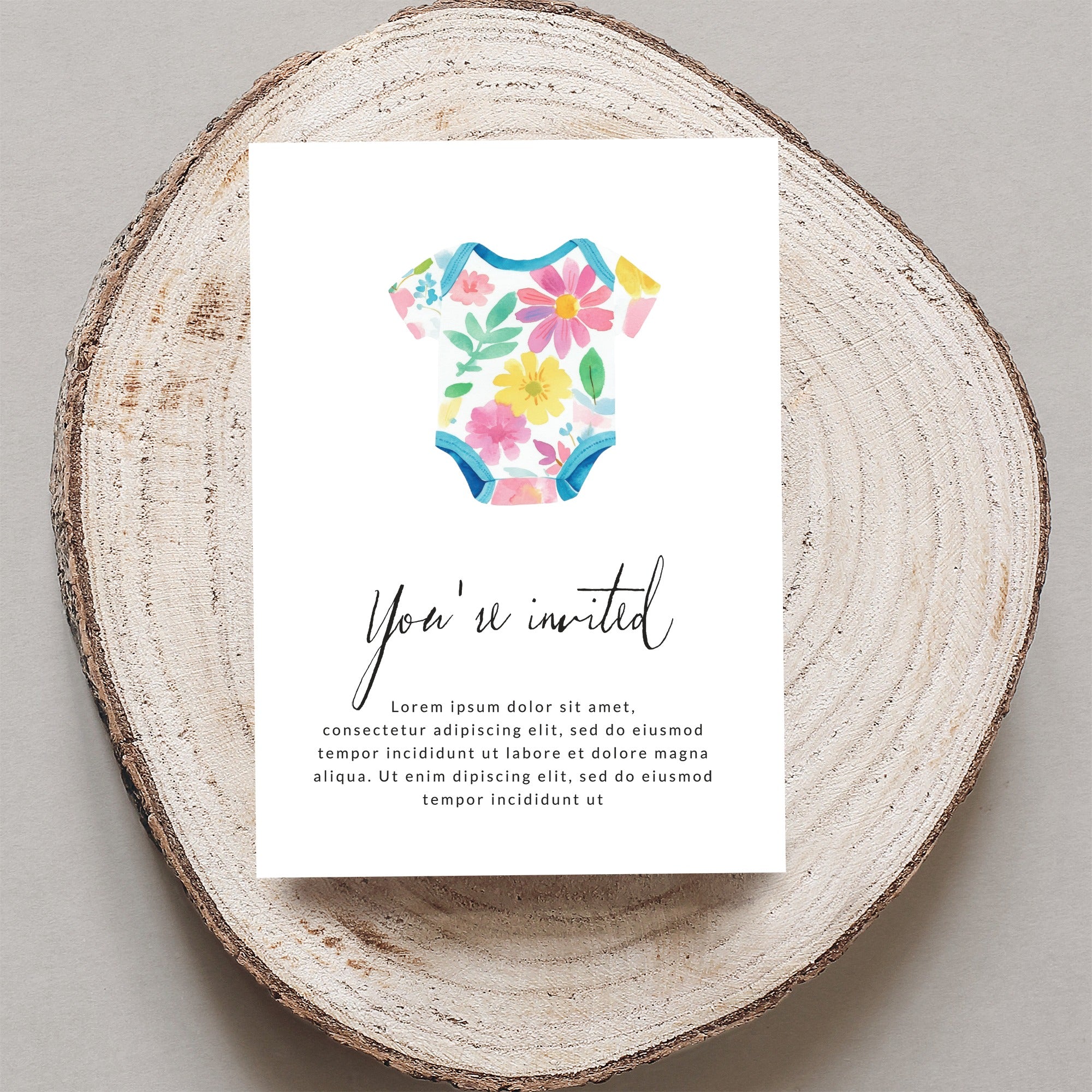 Baby bodysuit with floral pattern on a card reading "You're invited."