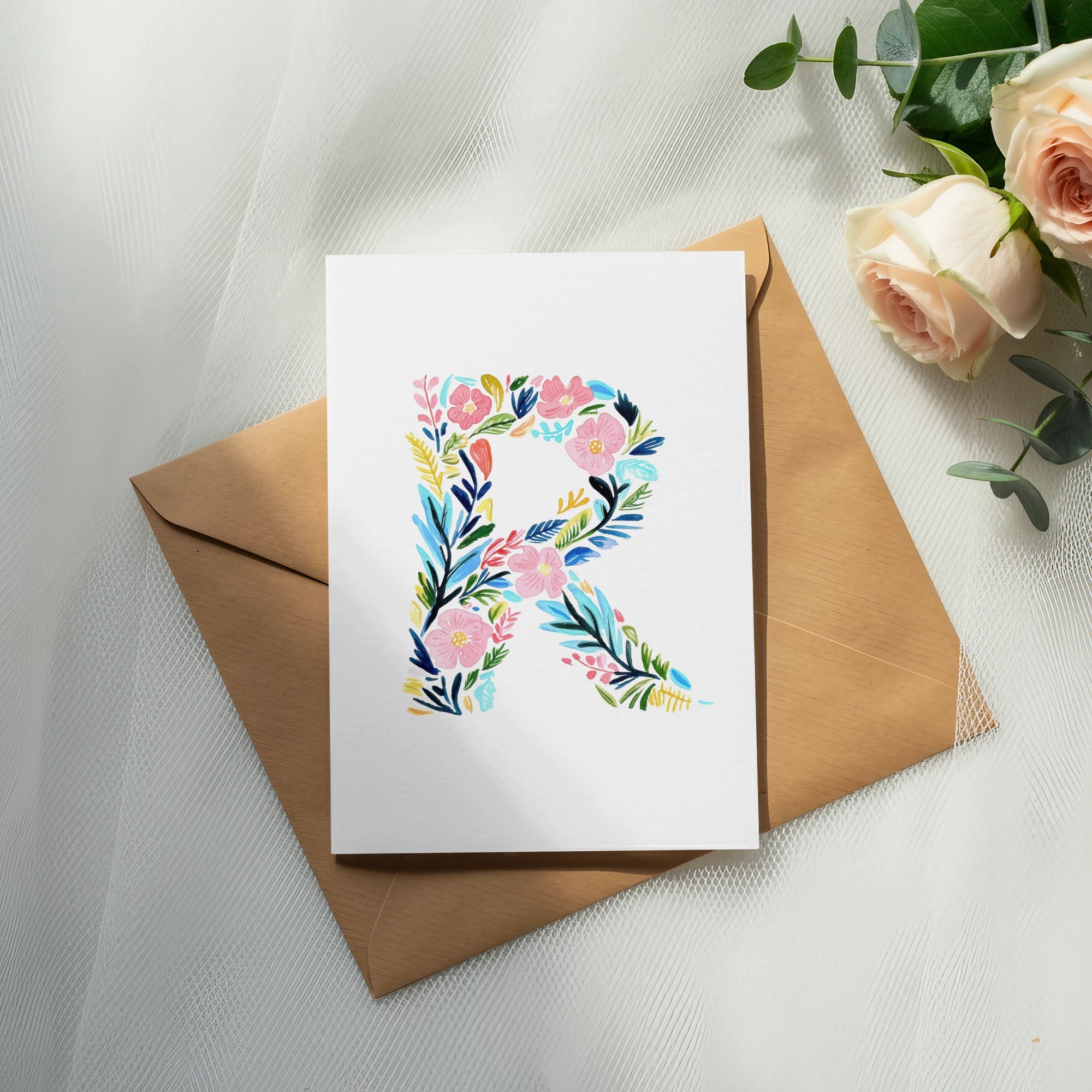 White card with letter R made of colorful flowers on brown envelope.