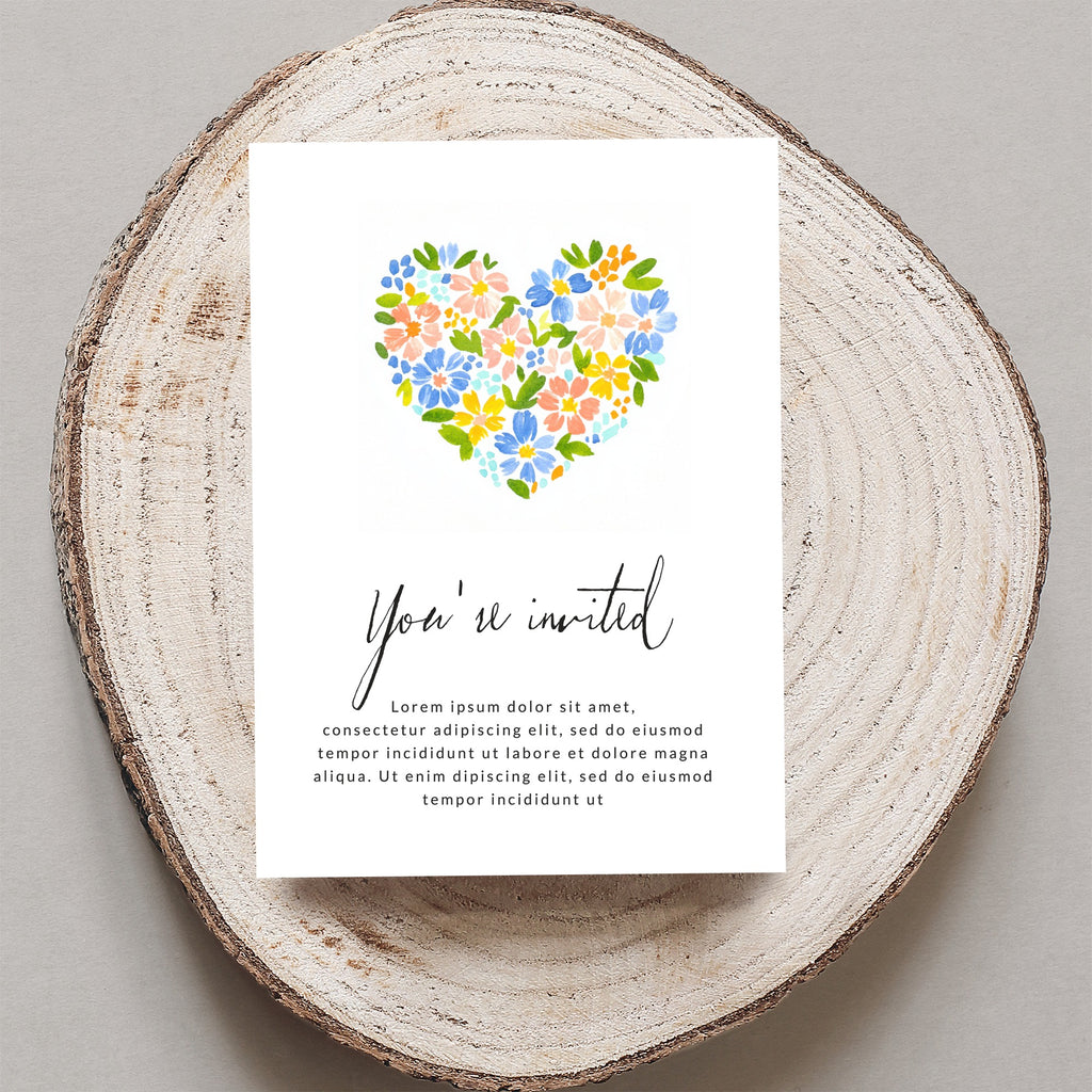 Invitation with floral heart and placeholder text, on a wood slice.