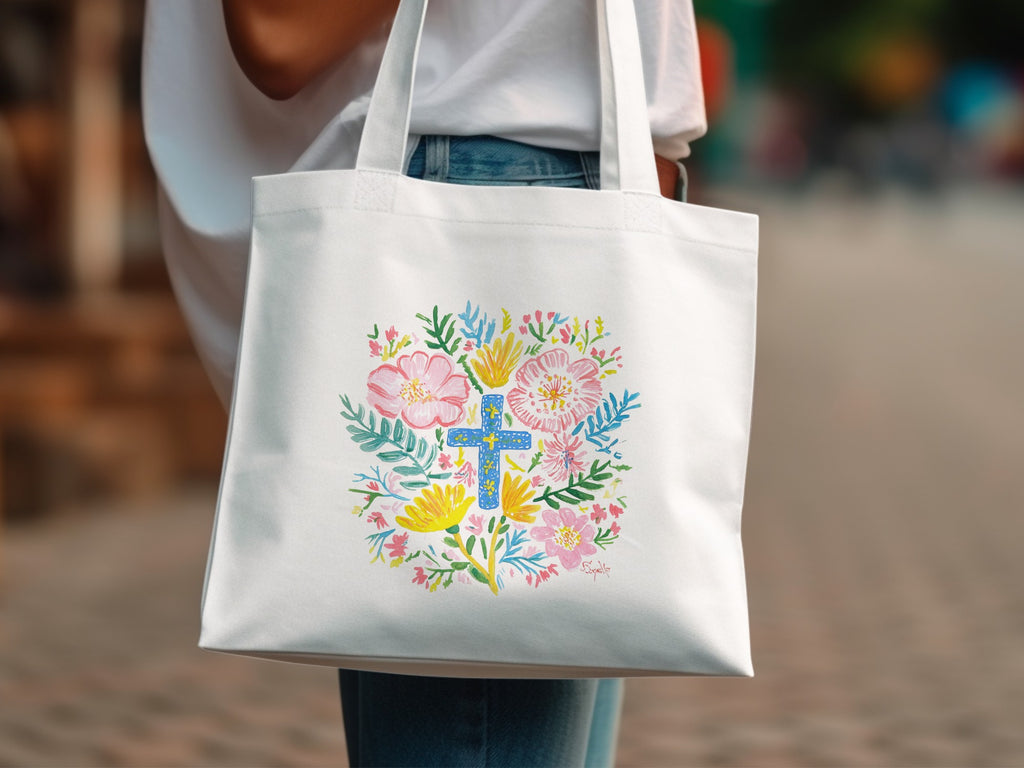 White tote bag with a colorful floral cross design.