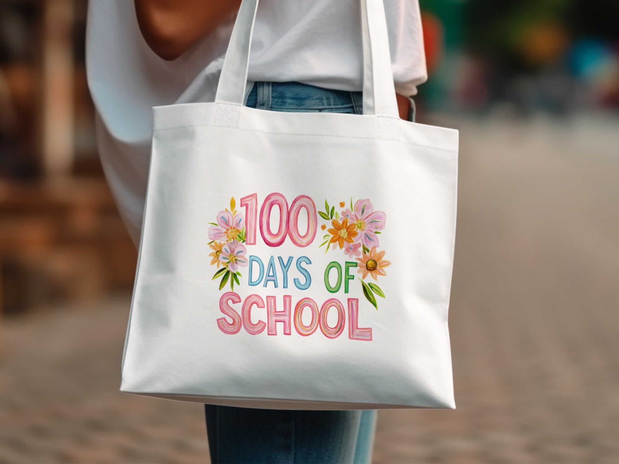 White tote bag with "100 Days of School" text and floral decorations.
