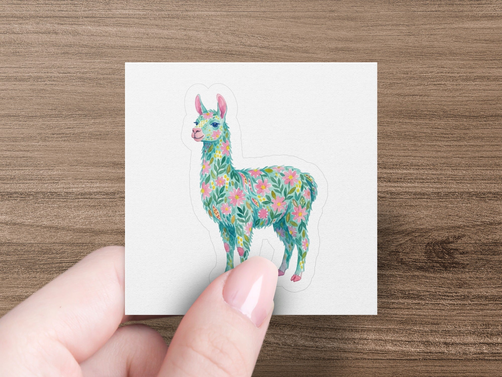 Floral llama sticker with pastel colors held by fingers.