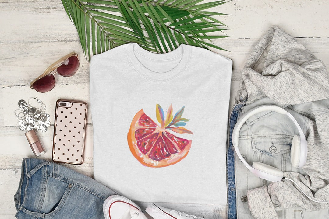 White t-shirt with watercolor orange slice graphic, styled with clothes and headphones.