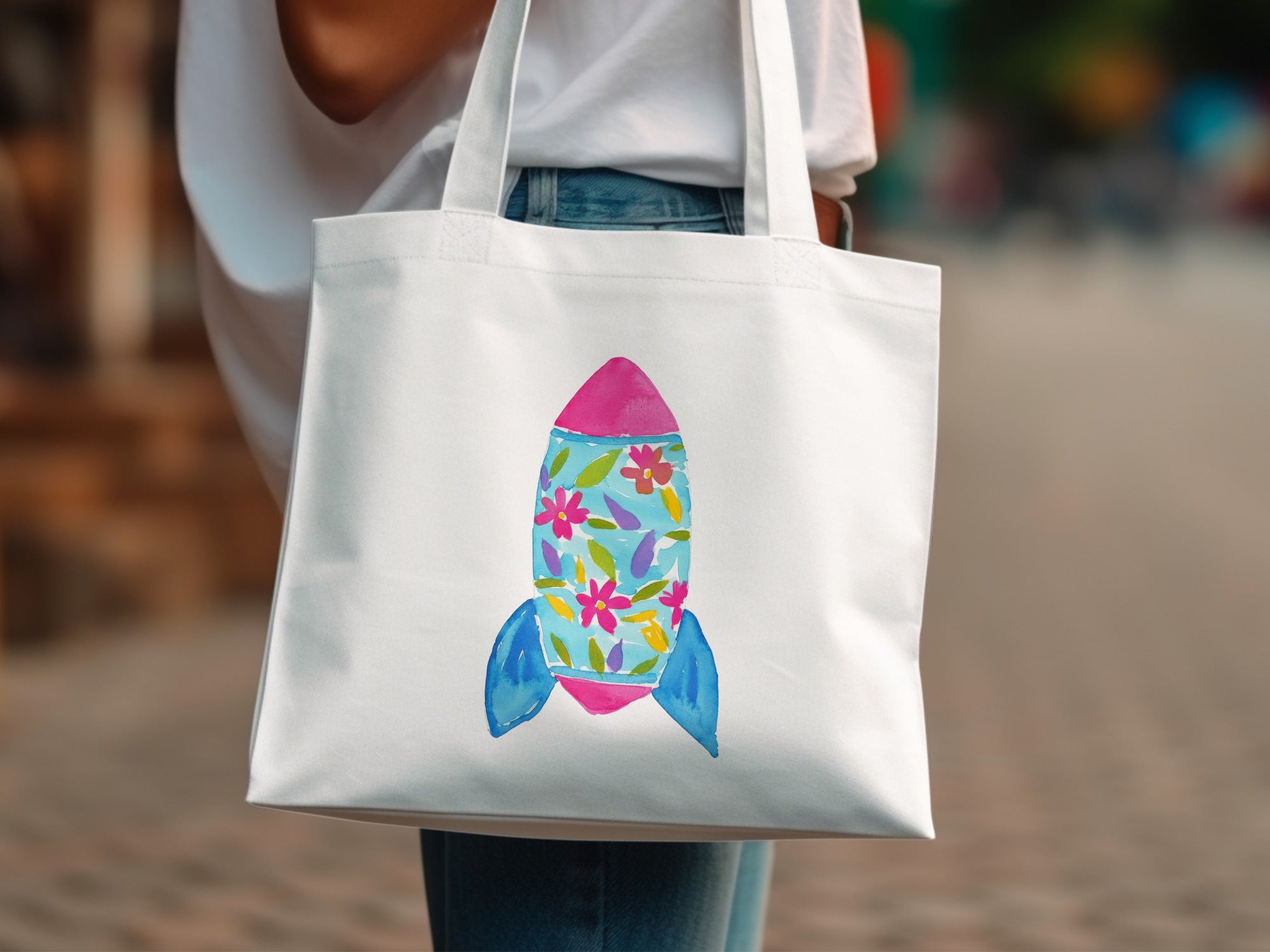 White tote bag with a colorful rocket ship design.