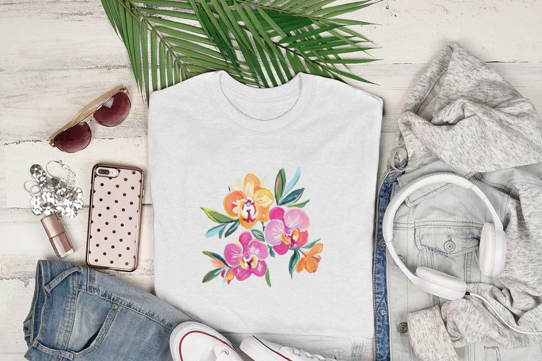 White t-shirt with colorful orchid floral graphic, flat lay with clothing and accessories.