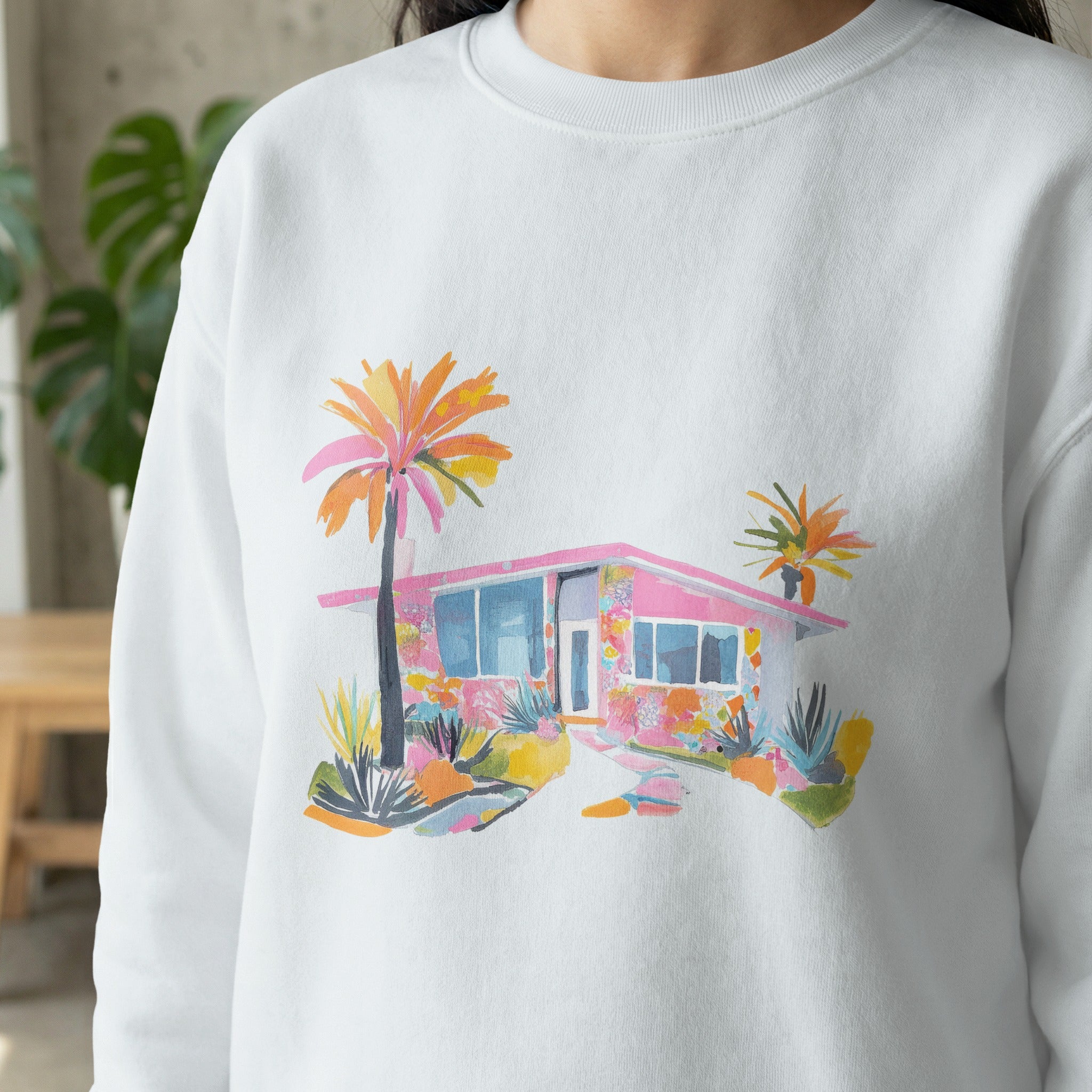 White sweatshirt with colorful Mid-century modern house and palm tree graphic.