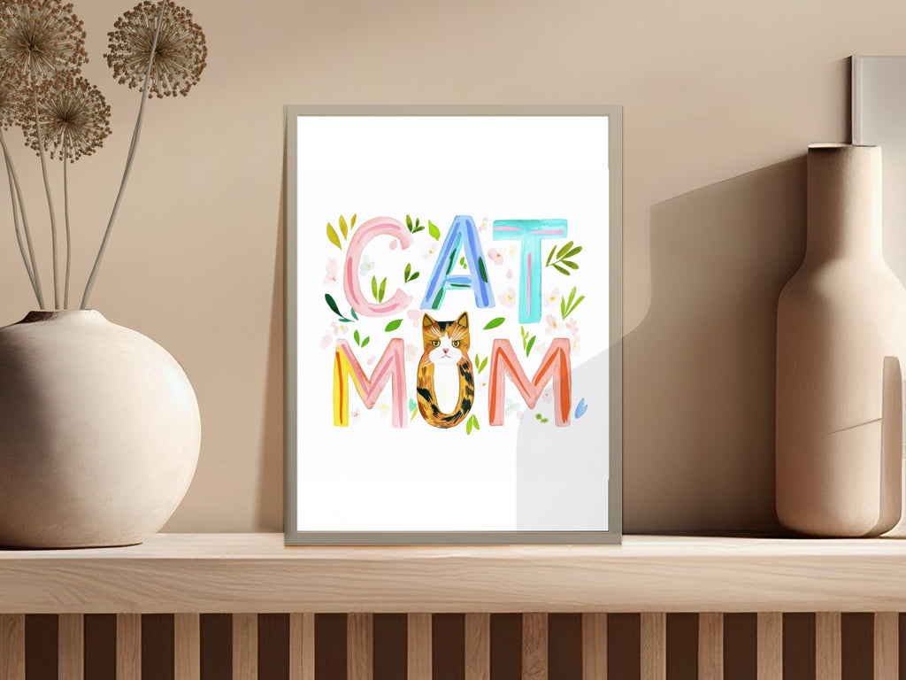 Colorful text "CAT MOM" above a cat illustration in a framed print.