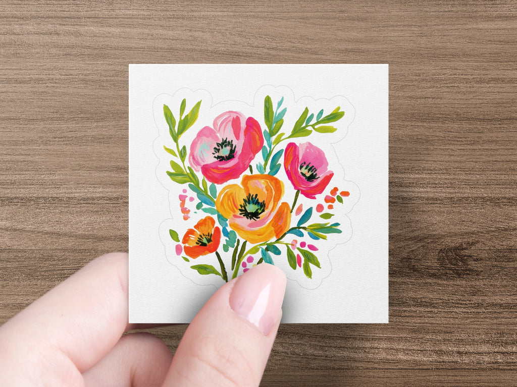Watercolor bouquet of poppies in pink, orange, and red with green leaves.