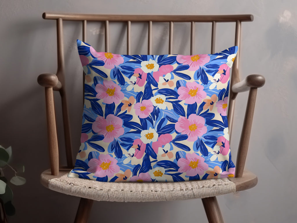 Floral pattern pillow with pink, blue, and cream flowers on a wooden chair.