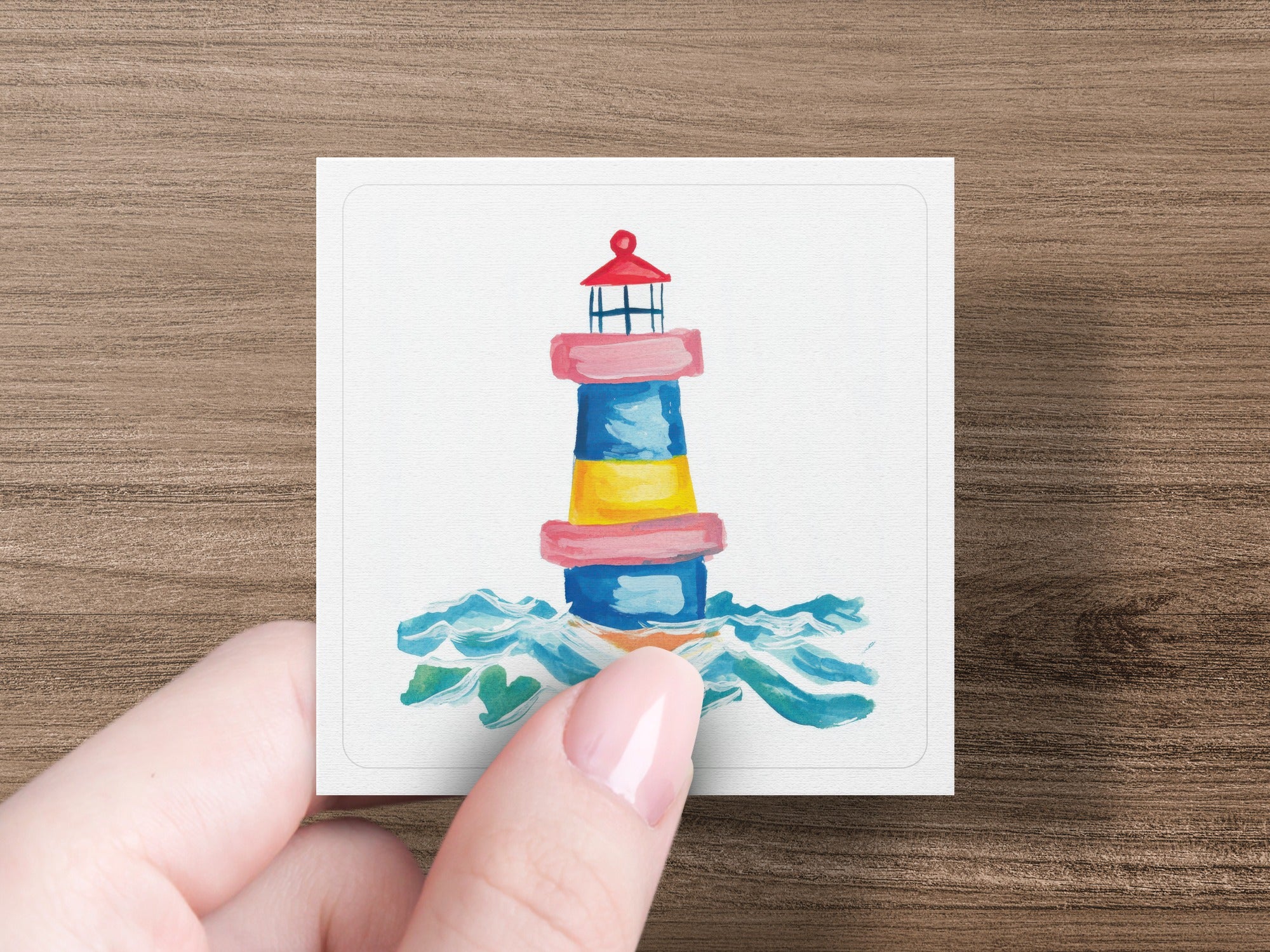 Colorful lighthouse with waves on card held by hand.
