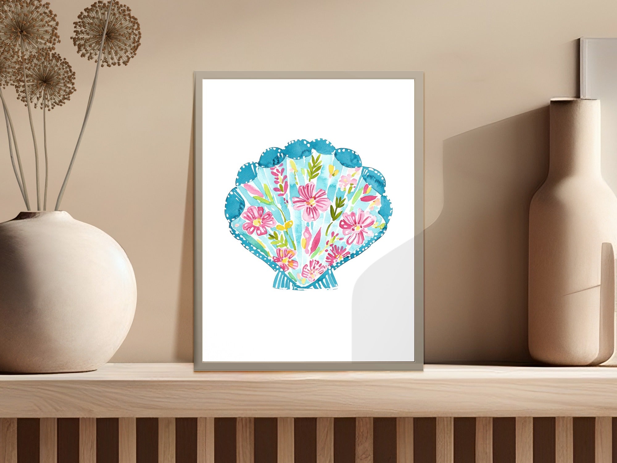 Watercolor painting of a pink and blue scalloped seashell with floral accents.