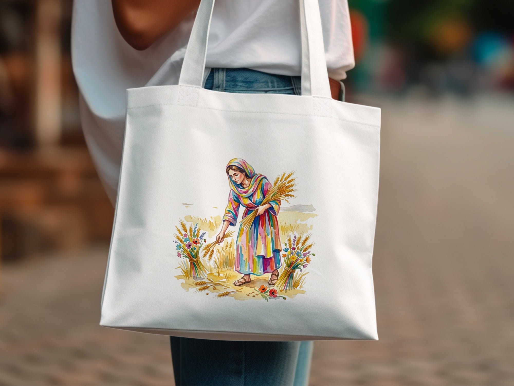 Woman in colorful dress holding wheat stalks and flowers on a white tote bag.