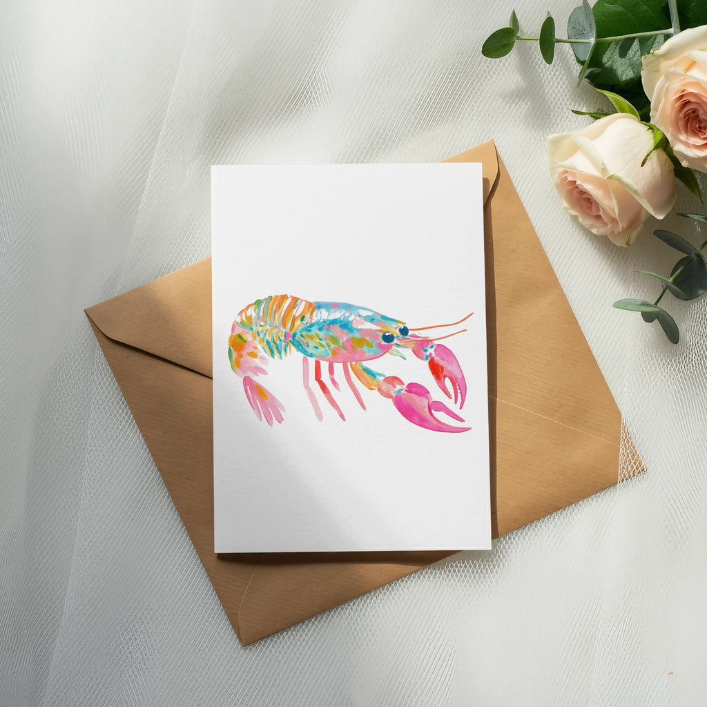Watercolor lobster illustration on a card atop an envelope with roses.
