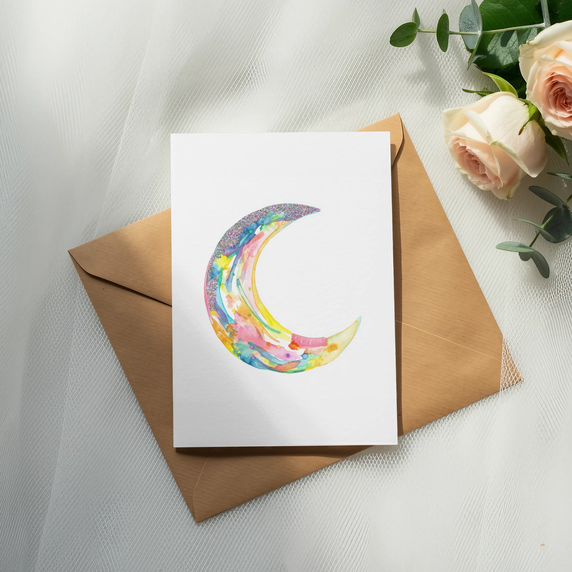 Watercolor crescent moon illustration on card with roses and envelope.