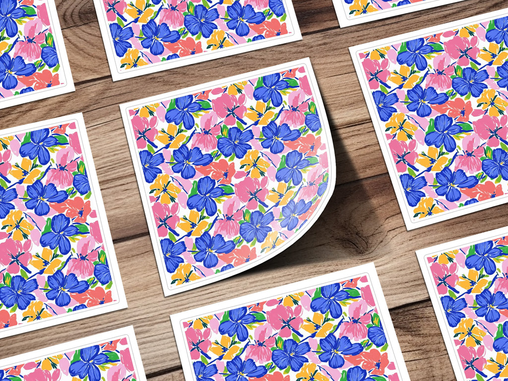 Floral pattern on cards with blue, pink, and yellow flowers on a wooden surface.