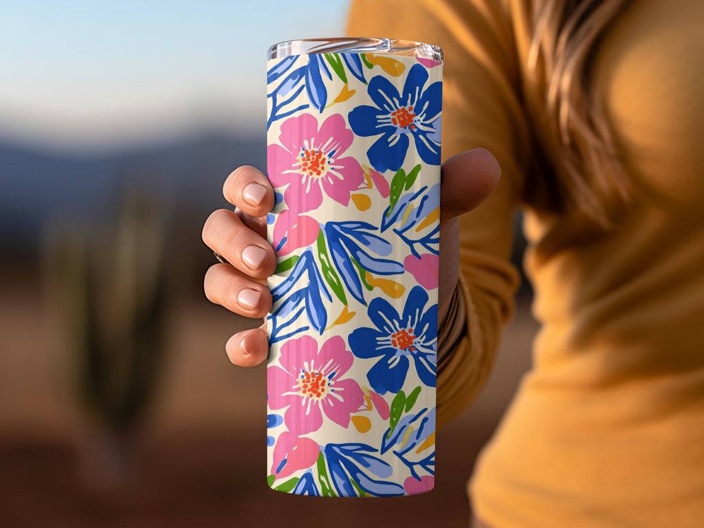 Tan tumbler with pink and blue floral pattern held by hand.