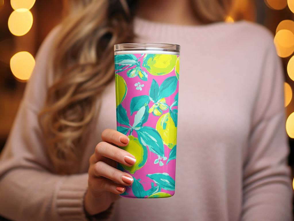 Woman holding a pink tumbler with a teal lemon and leaf pattern.