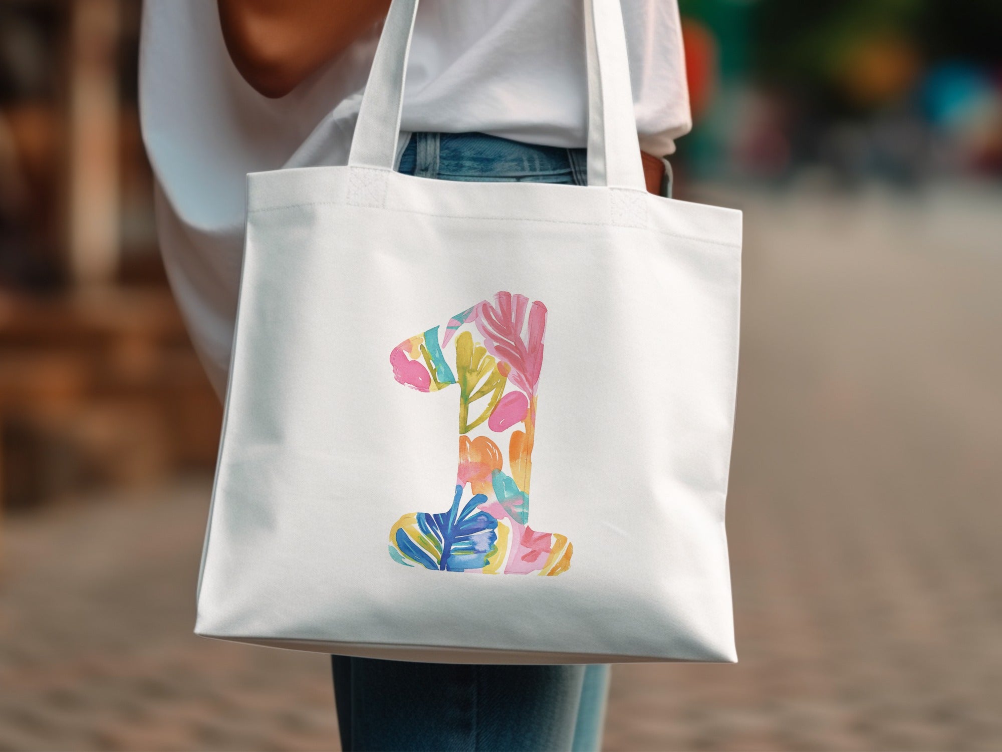 White tote bag with colorful floral "1" design.
