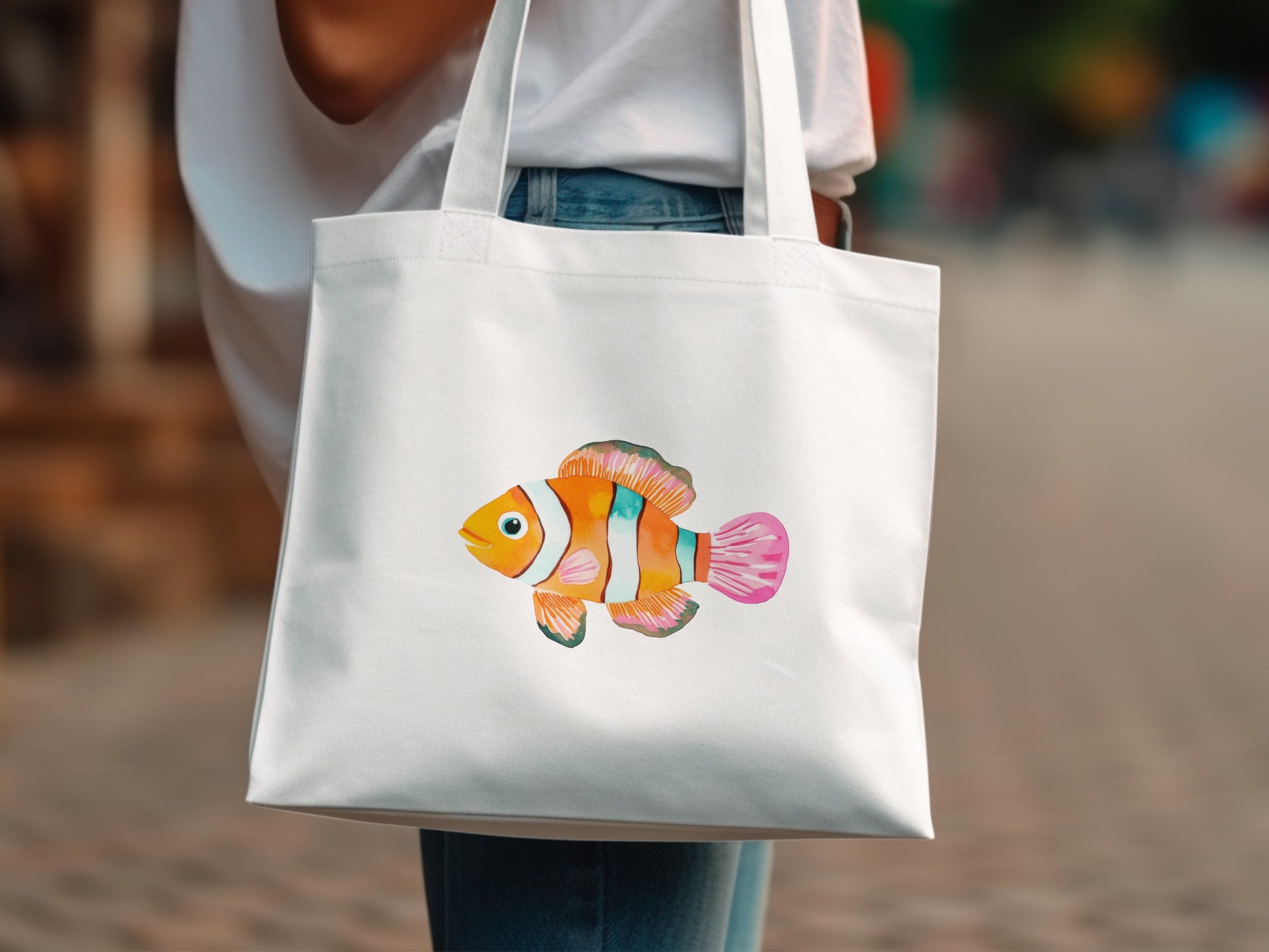 White tote bag with a colorful watercolor clownfish illustration.
