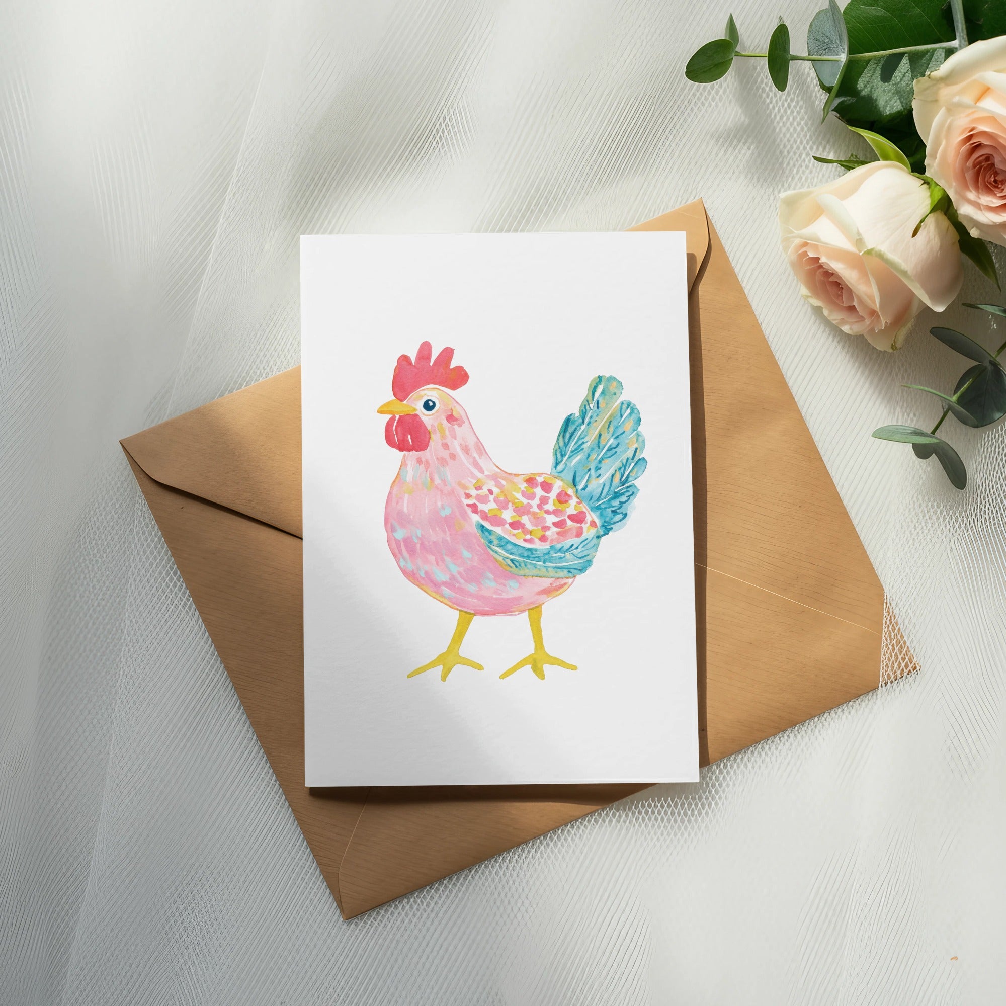Watercolor illustration of a pink and blue chicken on a white card atop a brown envelope.
