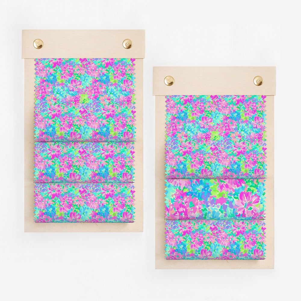 Two swatches of fabric with a vibrant floral pattern of pink, blue, and green.