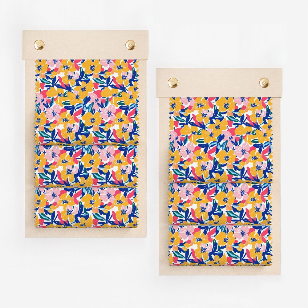 Two fabric swatches with a vibrant floral pattern of pink, blue, and yellow flowers.
