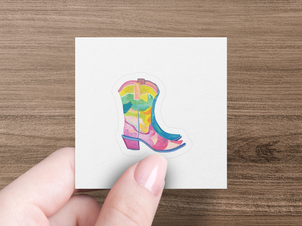 Colorful cowboy boot sticker on a white background held by fingers.
