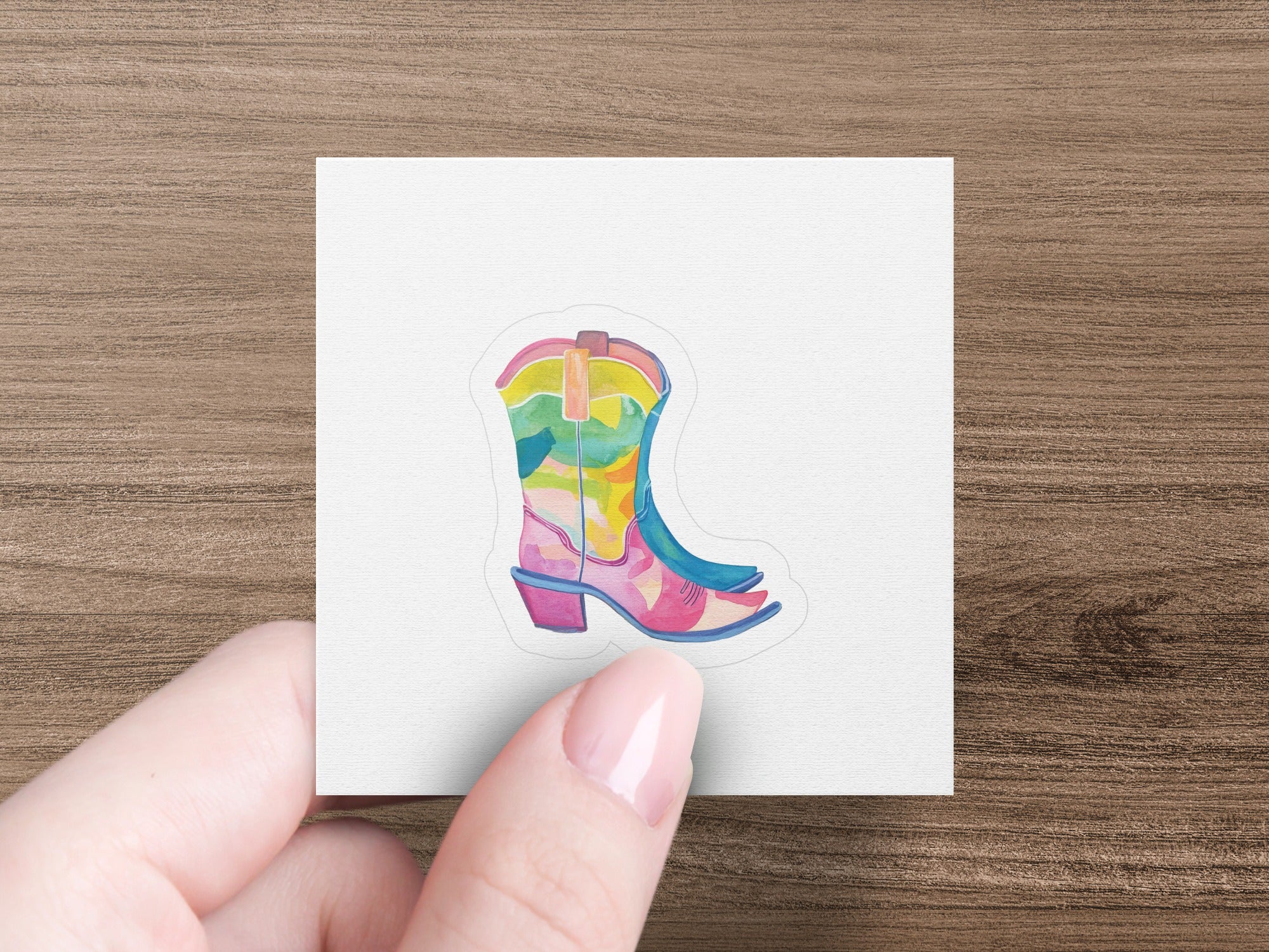 Colorful cowboy boot sticker on a white background held by fingers.