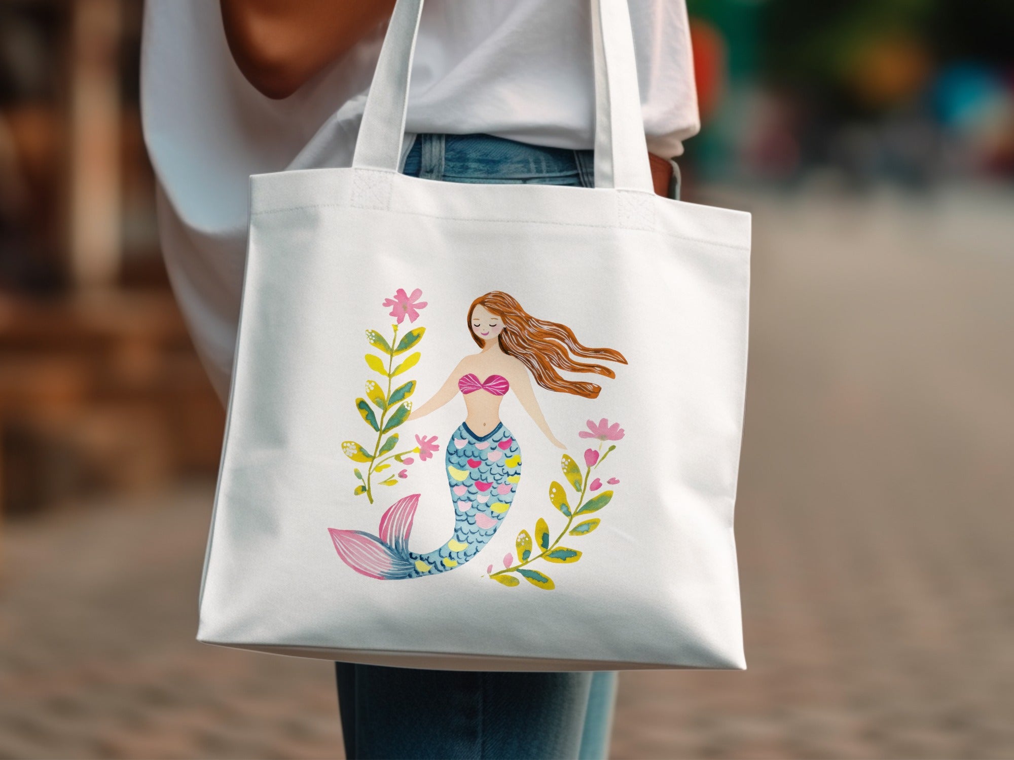 Tote bag with watercolor illustration of a mermaid surrounded by floral accents.