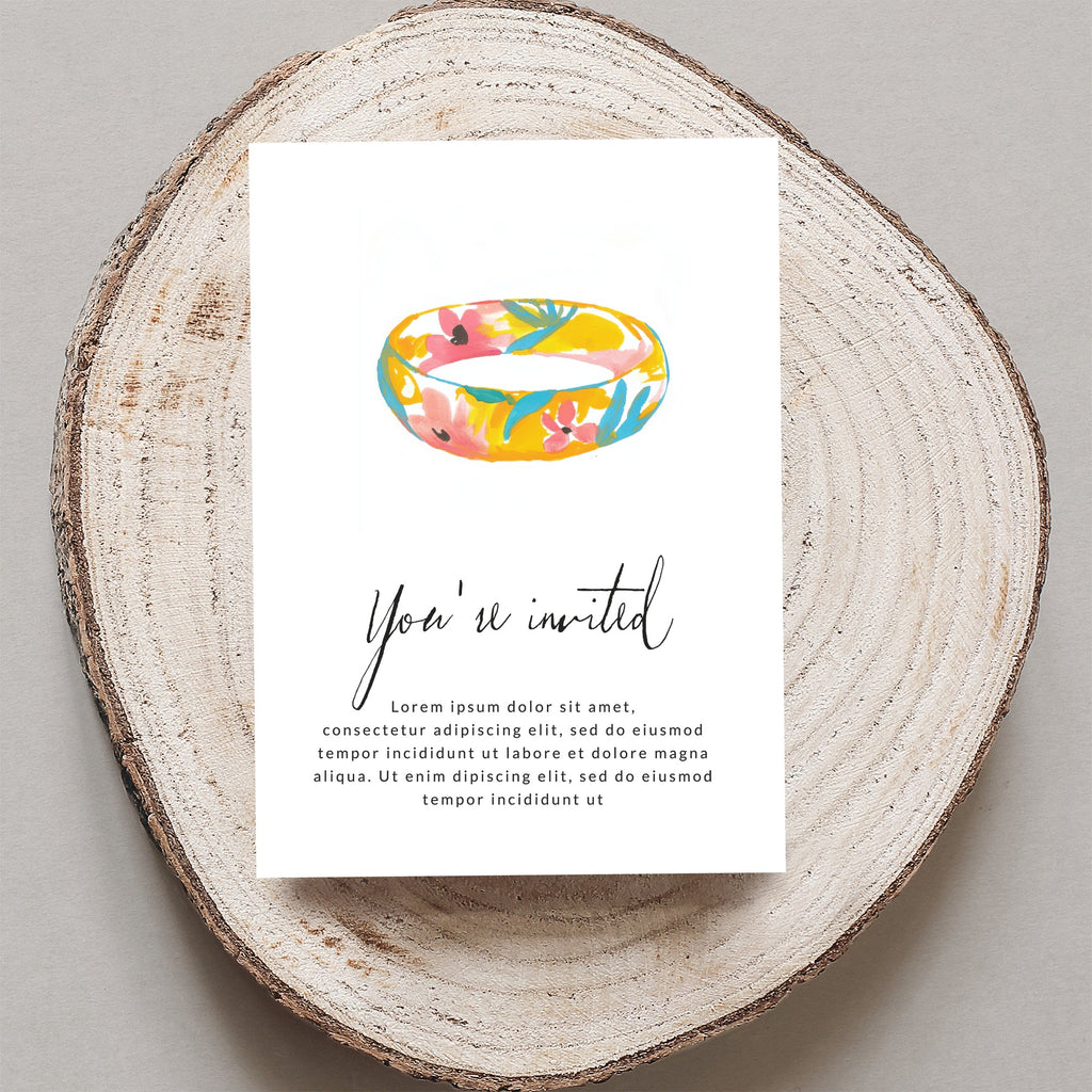 Floral ring invitation on wood slice with "You're invited" text.