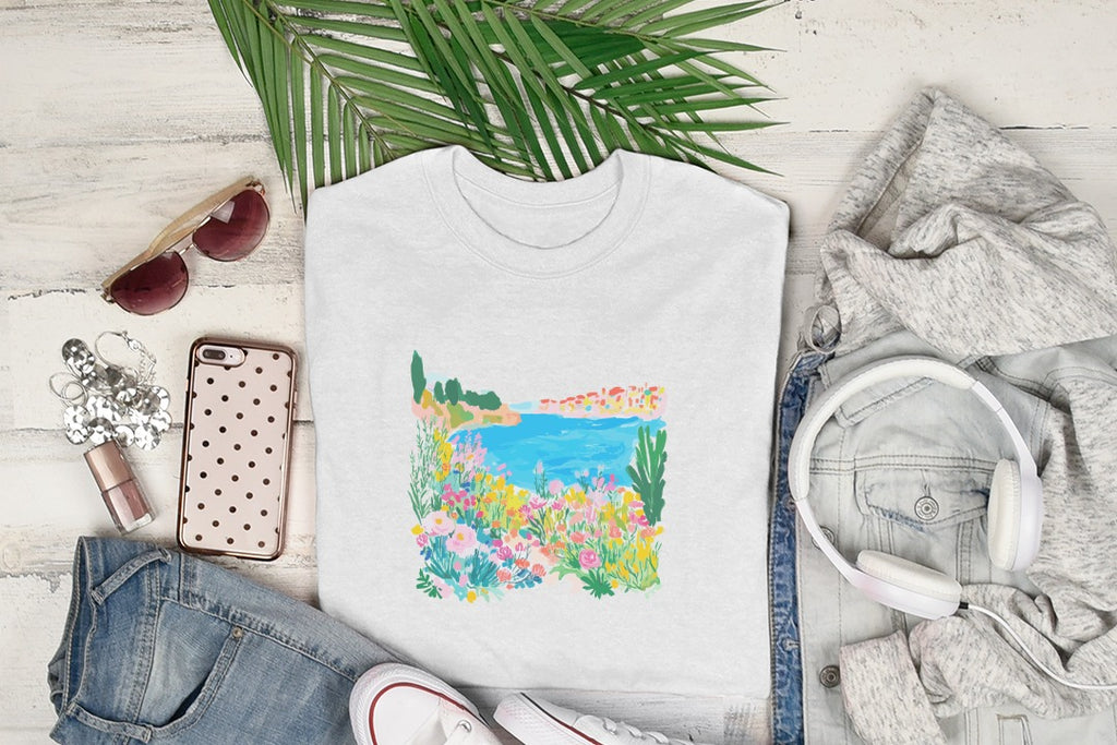 White crewneck t-shirt with a colorful floral and seaside graphic.