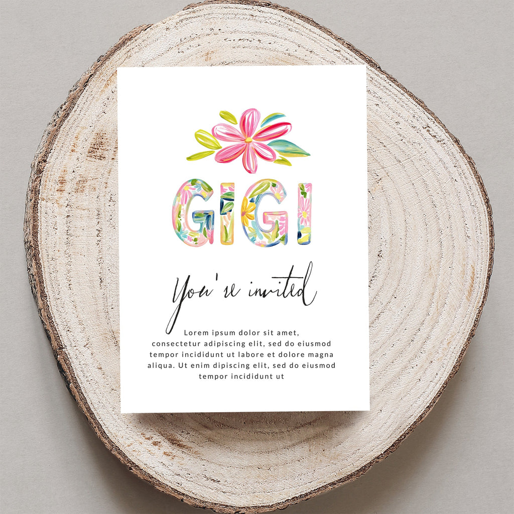 "Gigi You're invited" card with floral letters on wood slice.