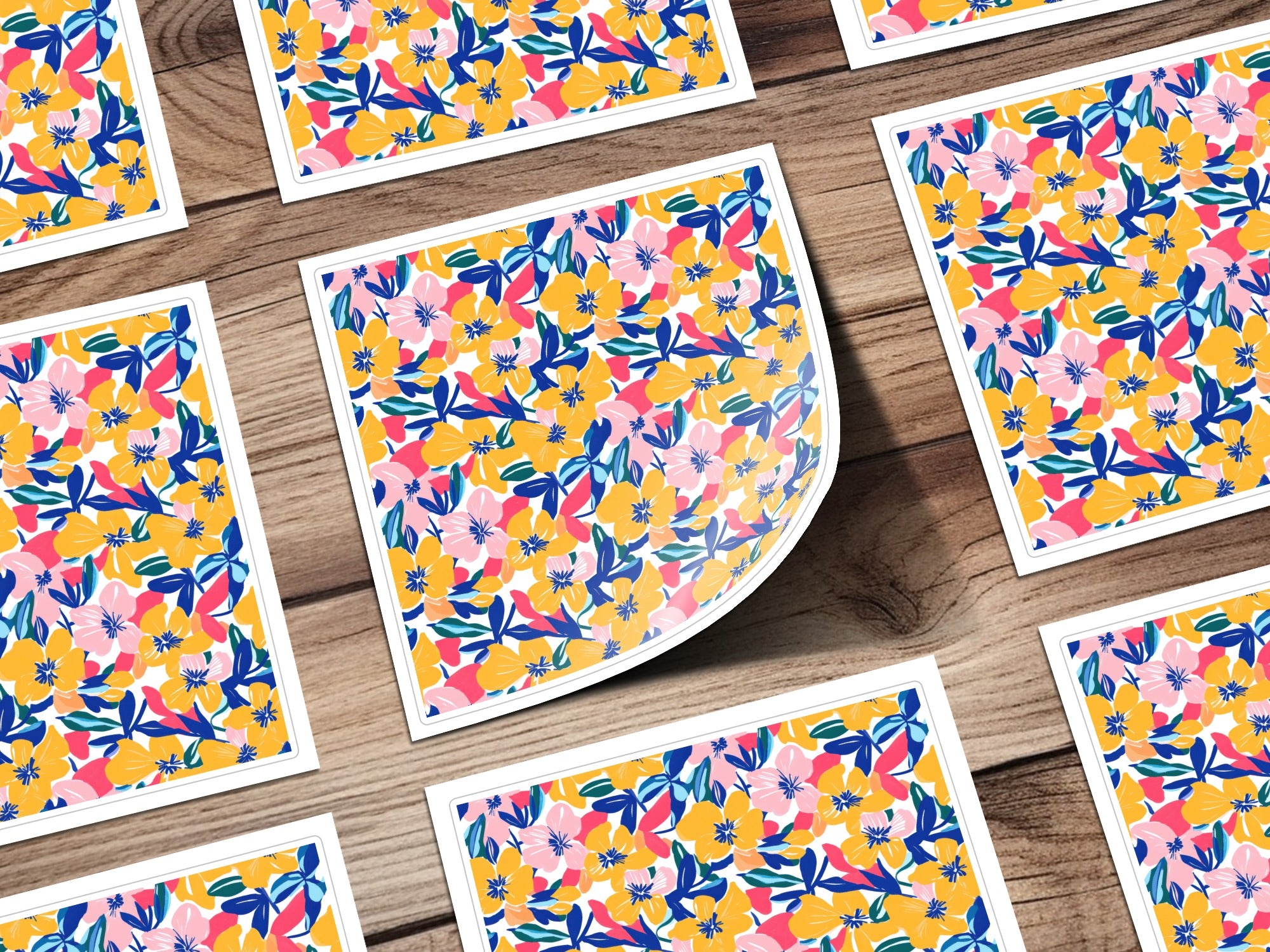 Several square cards with a floral pattern of pink, blue, and yellow flowers on a wooden surface.