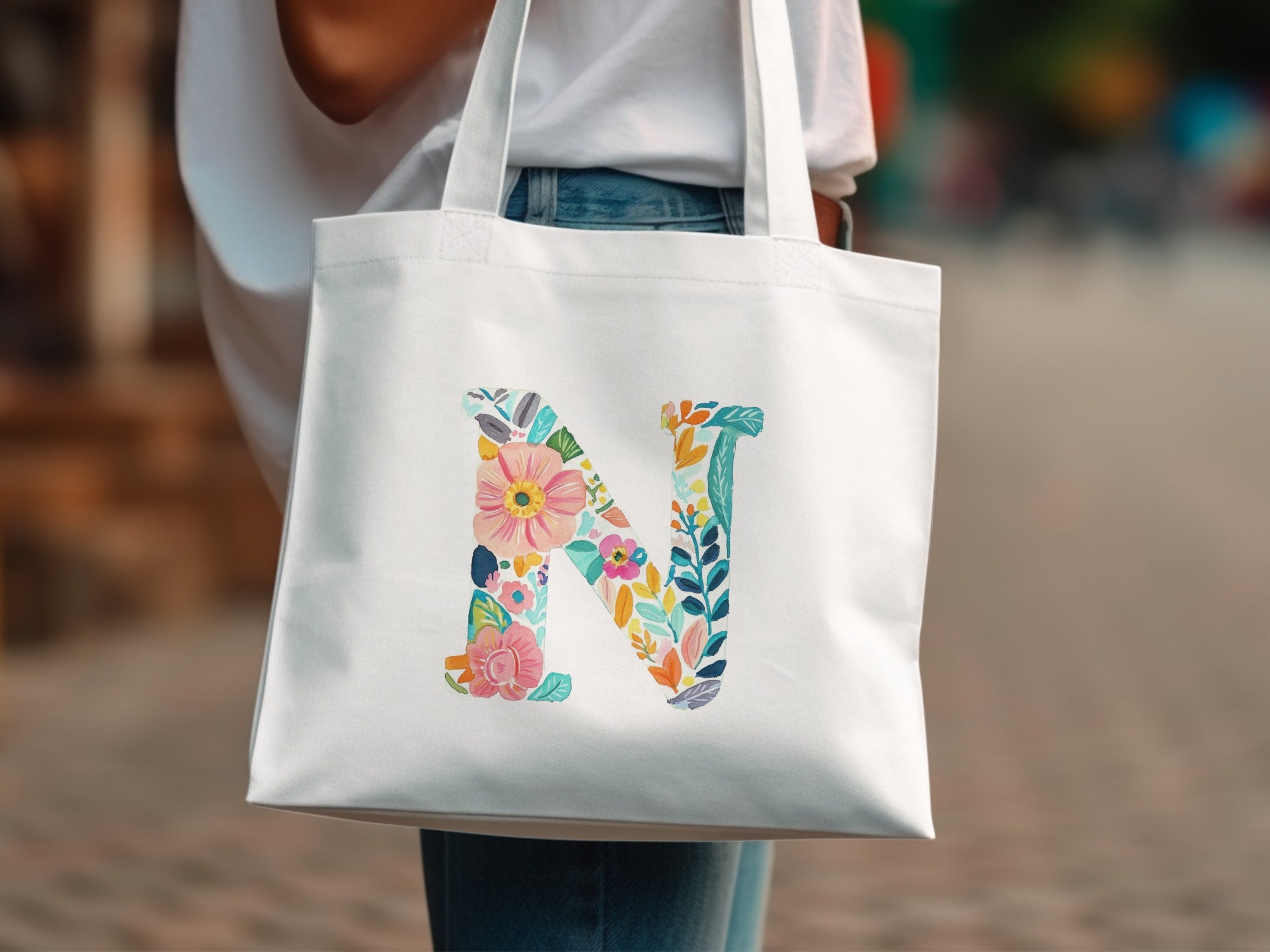 White tote bag with a large, colorful floral letter 'N' design.