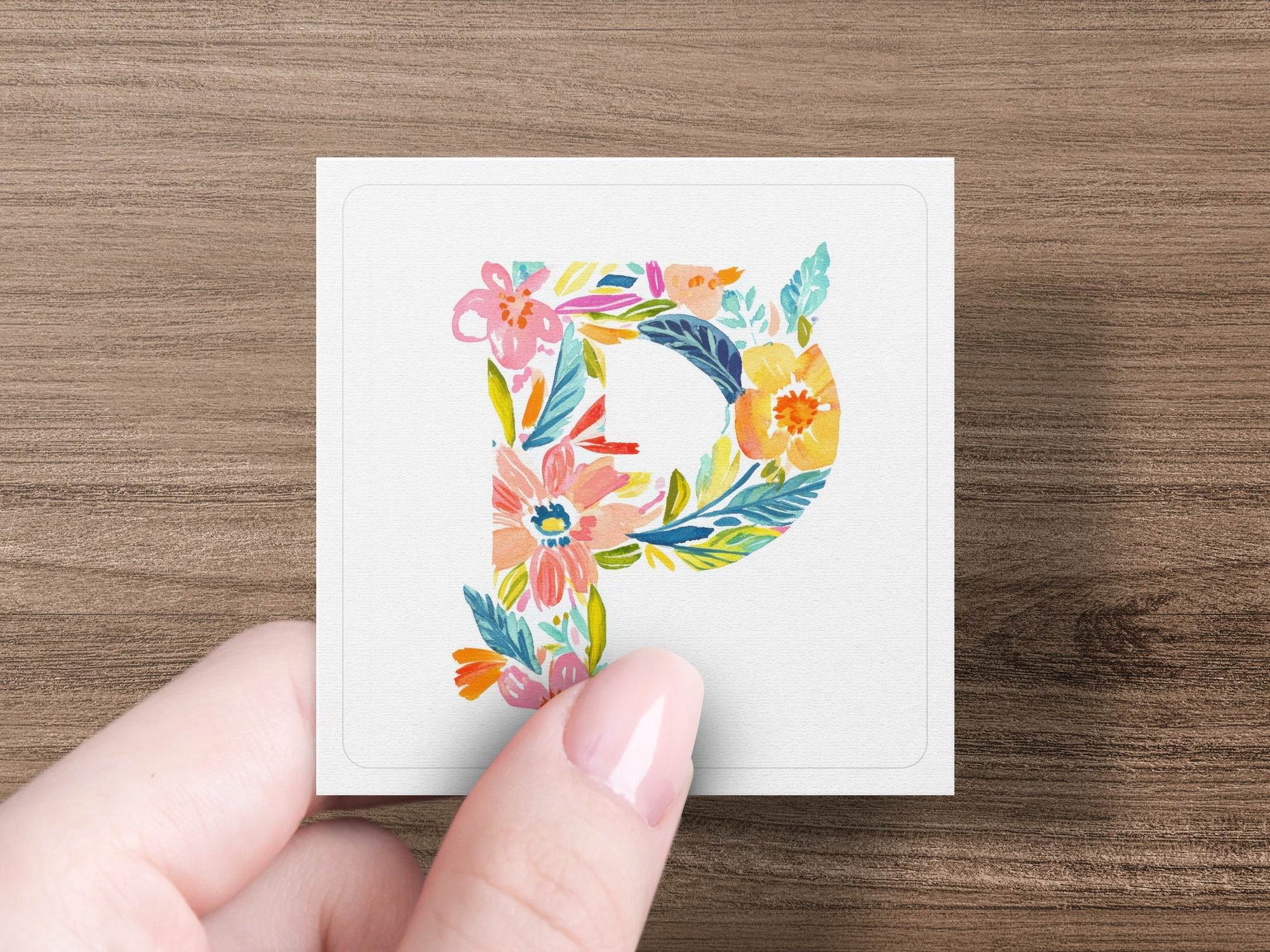 Floral letter P on textured paper held by fingers.