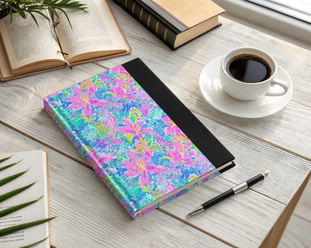Colorful floral journal with pen and coffee on a wooden desk.
