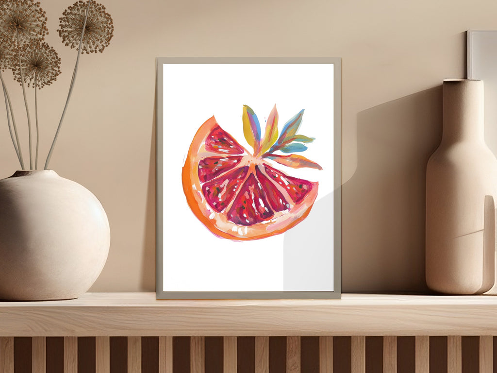 Watercolor painting of a sliced grapefruit with colorful leaves in a frame.