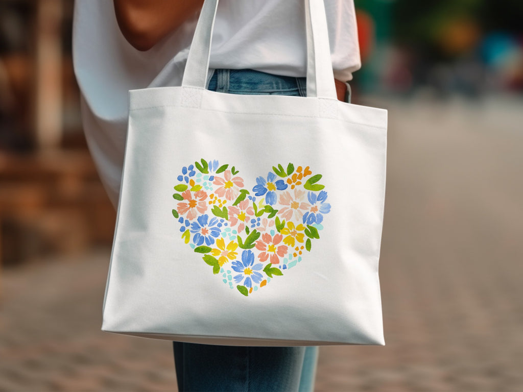 White canvas tote bag with a colorful floral heart design.