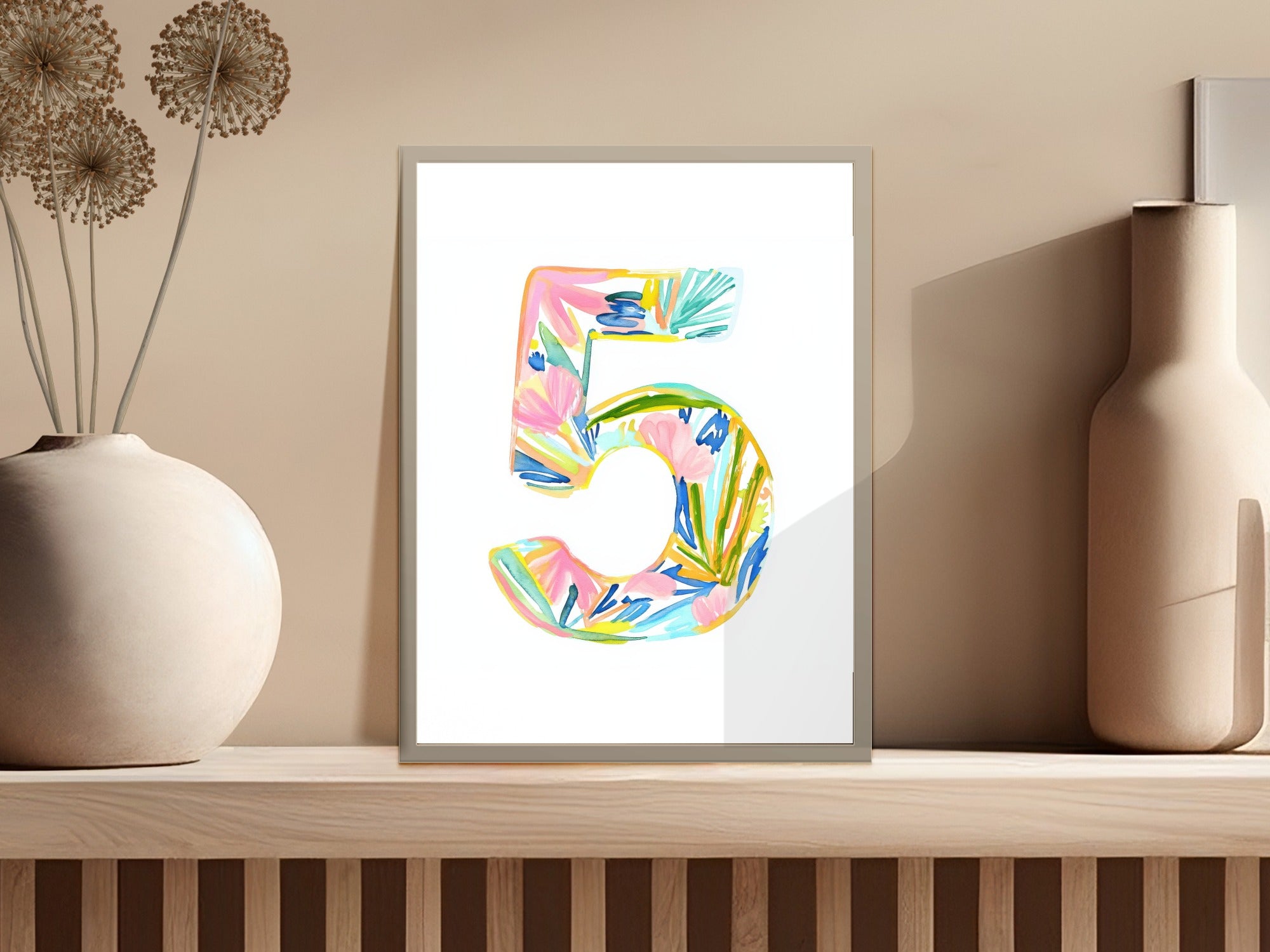 Colorful watercolor number 5 with floral accents on a shelf.