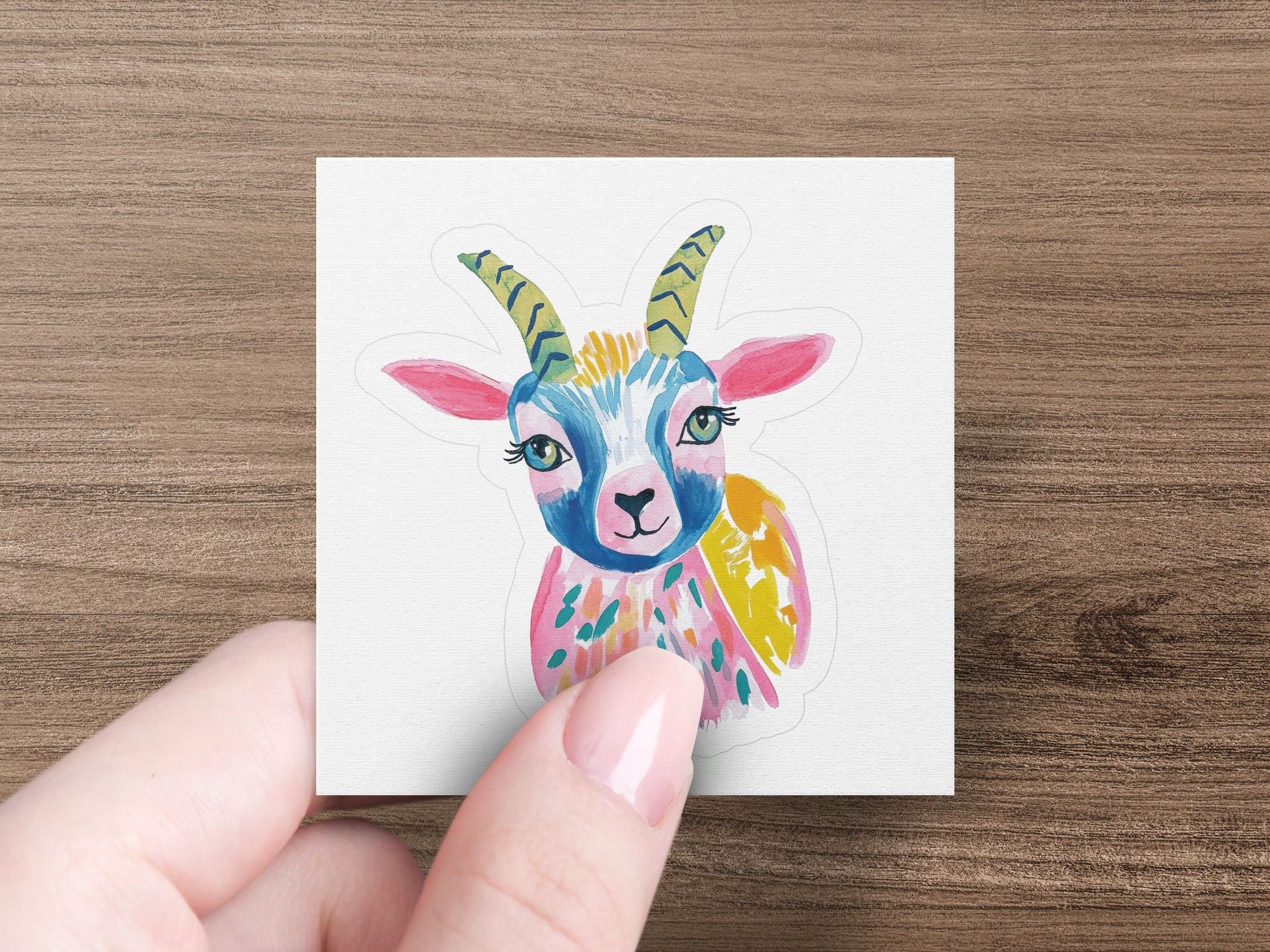 Stylized cartoon goat sticker with colorful markings and gold horns.