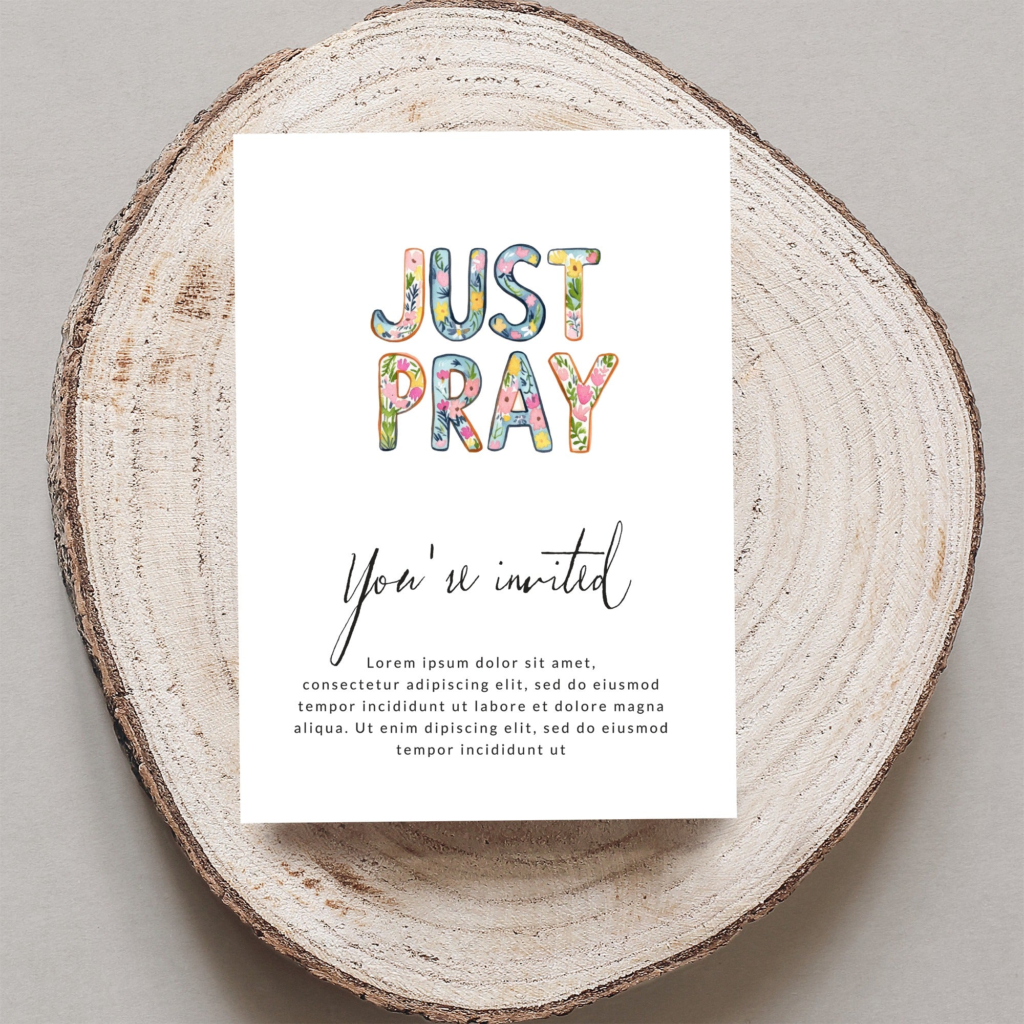 Card with "JUST PRAY" and "You're invited" text, on a wood slice.