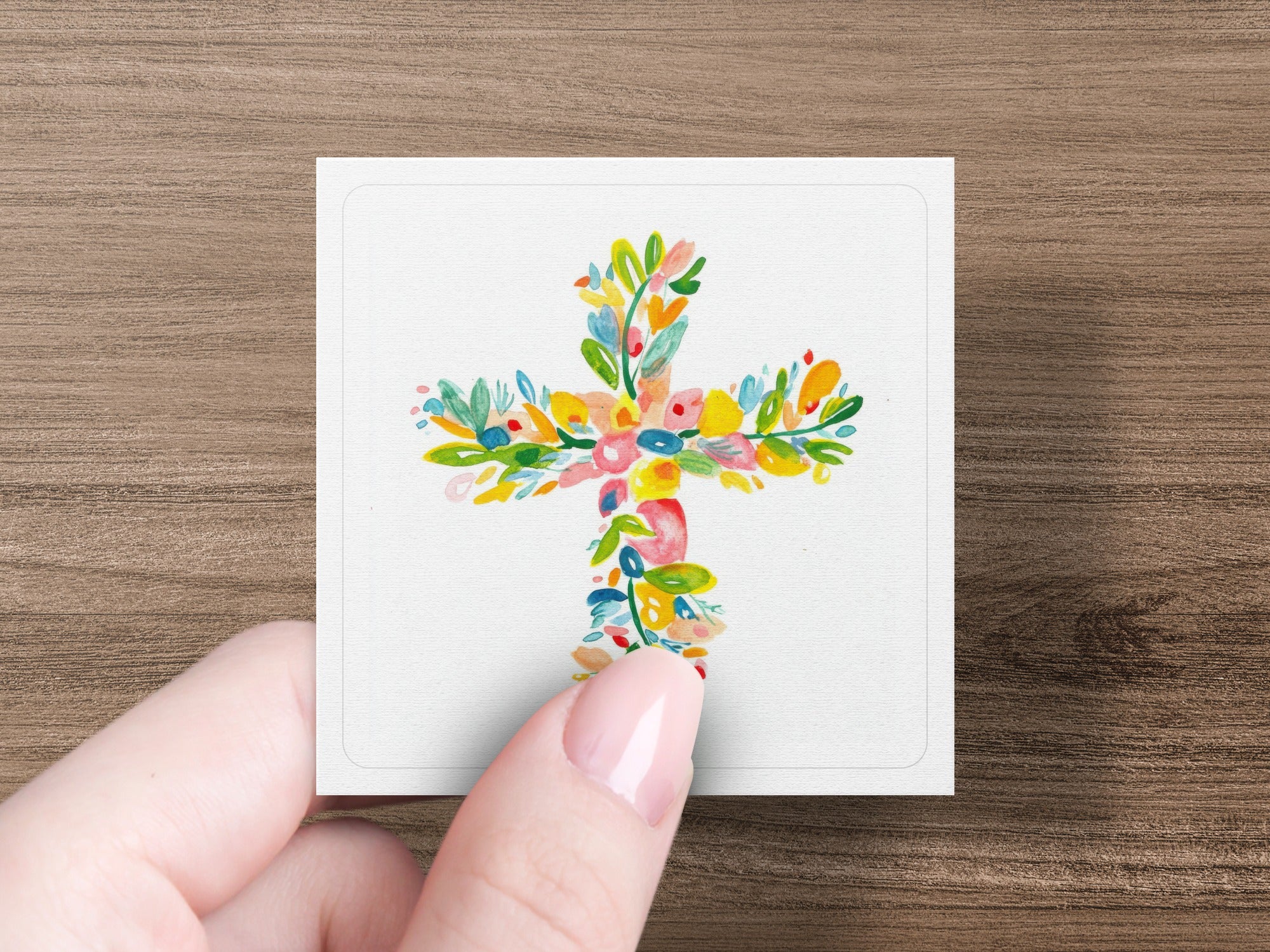 Floral cross design on a white card held by a hand.